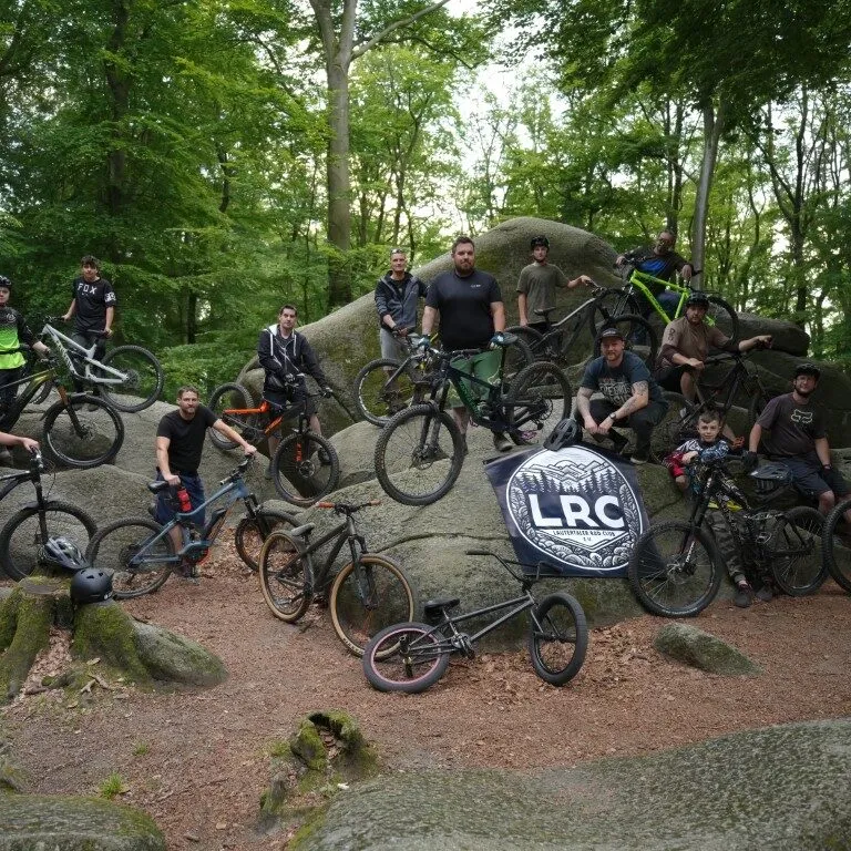 Gruppenfoto der Vereinsmitglieder mit Bikes auf Felsen im Wald